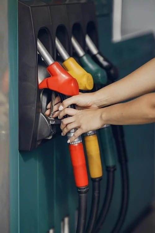 Unrecognizable female customer choosing fuel nozzle pump for filling car tank with gasoline on petrol station